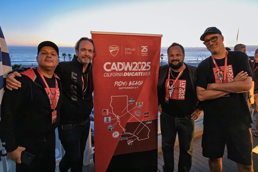 Four club members at the CADW 2025 step and repeat banner on the pier deck