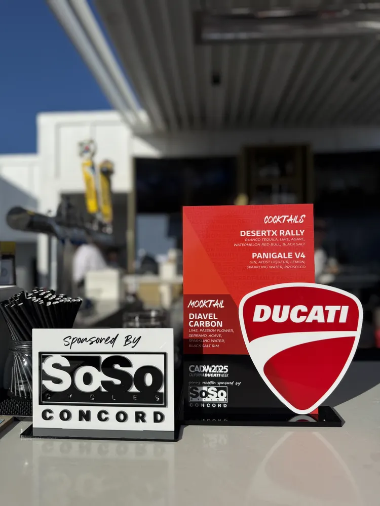 The Ducati shield beside the SoSo Cycles Concord sponsored cocktail menu at the gala