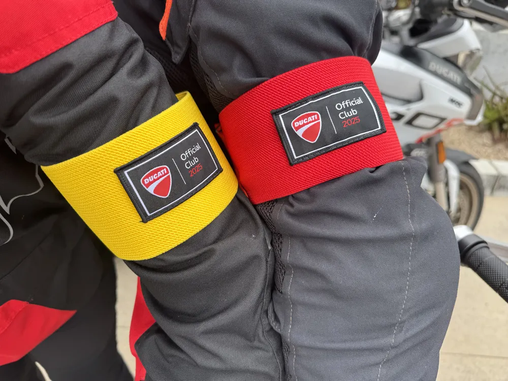 Two riders wearing red and yellow Ducati Official Club armbands over their leathers