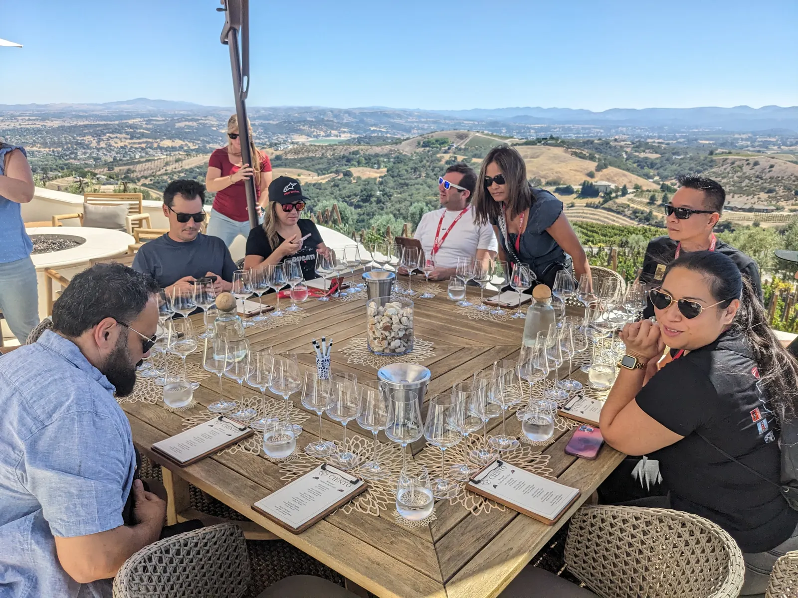Friends talking across a table set with tasting glasses on the terrace