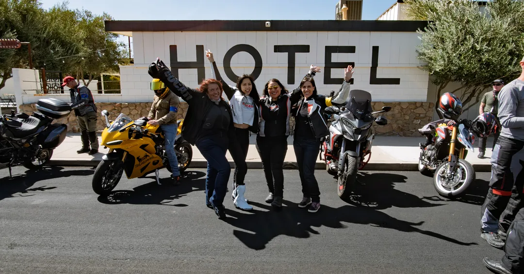 Riders posing beside their Ducatis in front of a hotel on Friday Ride B.