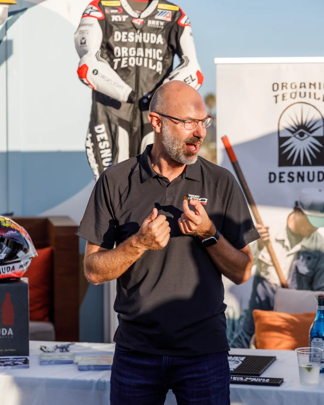 A speaker addressing attendees beside the partner banner at the Friday meet and greet.