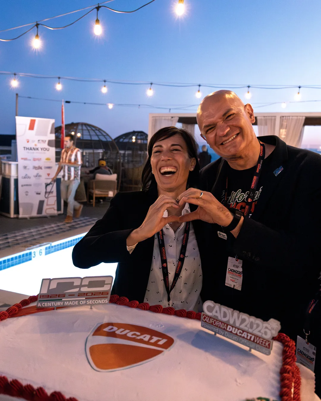 Two attendees smiling behind the Ducati cake at the Friday gala dinner.