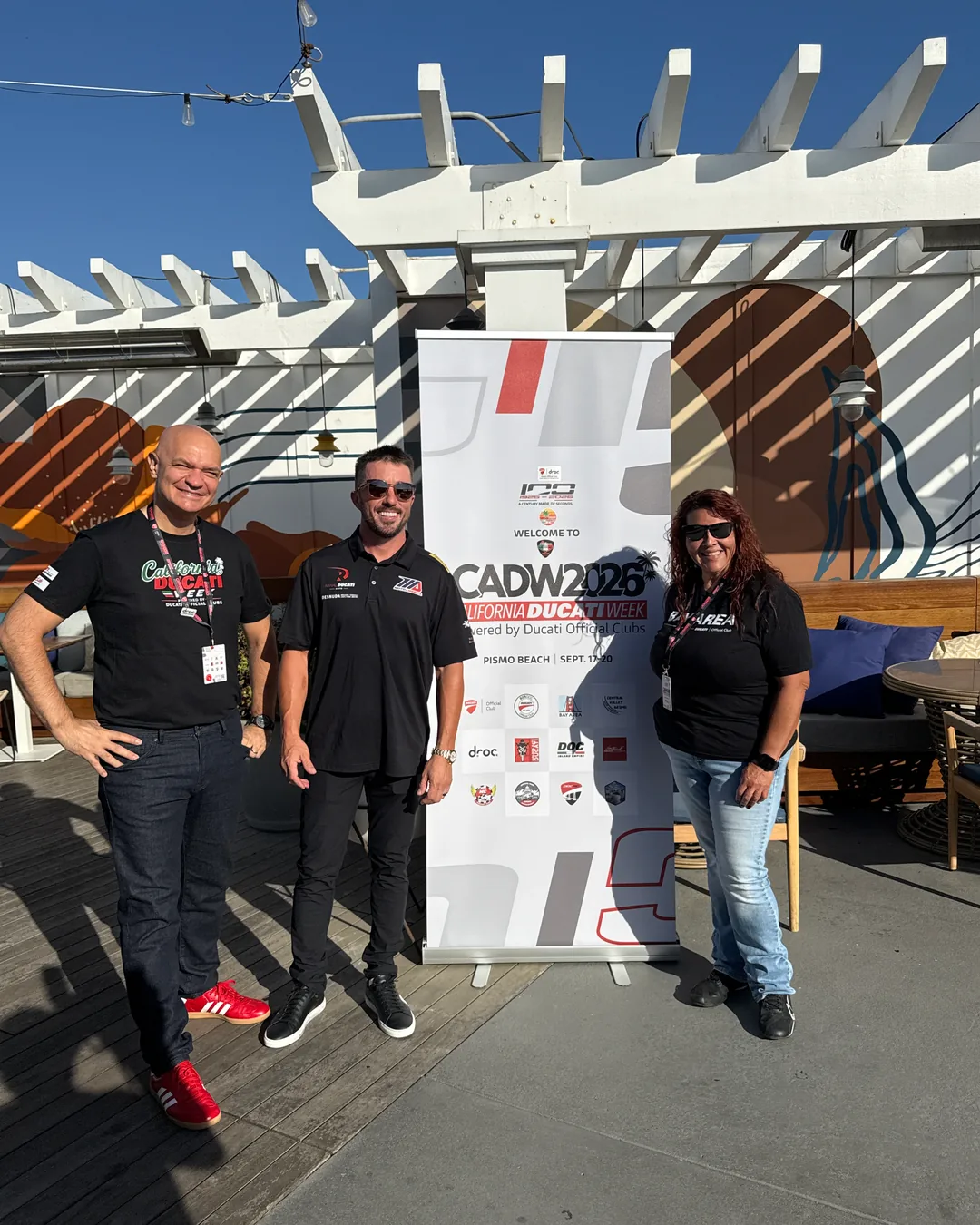 Attendees posing together in front of the CADW partner banner at the Friday meet and greet.