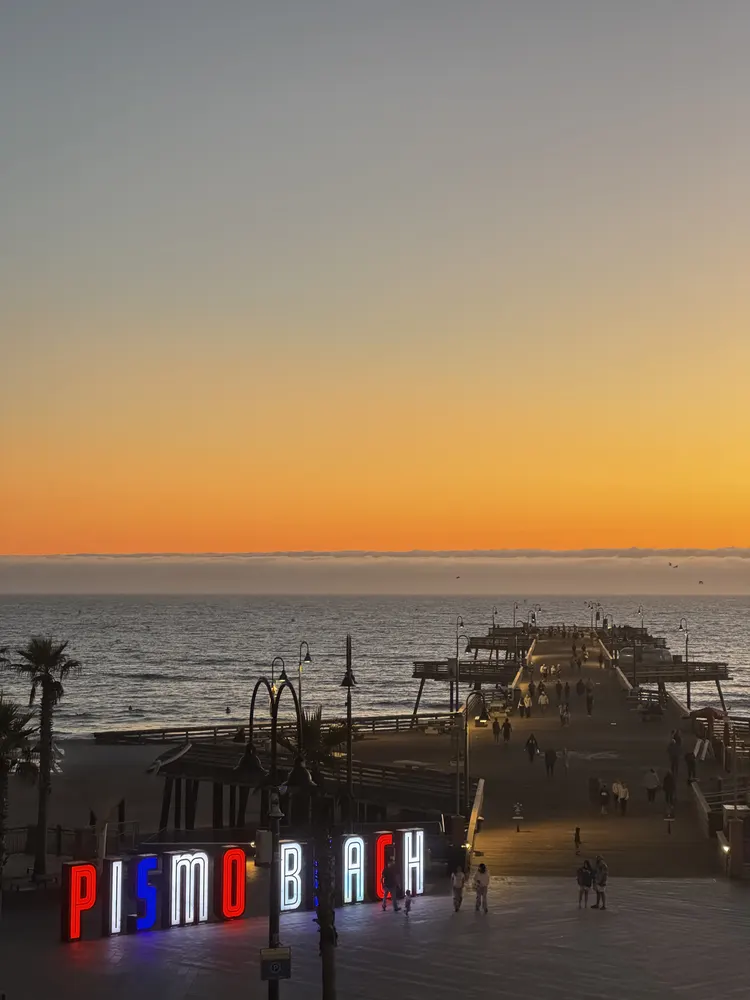 Sunset over the ocean at Pismo Beach with the lit pier sign