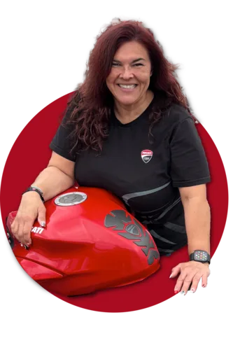 Tamu Bustos, President of the Bay Area Ducati Official Club, kneeling beside a red Ducati
